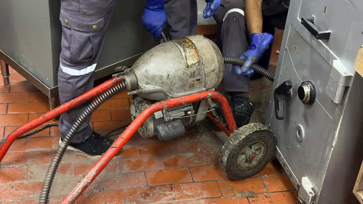 Electric drain cleaning machine feeding a steel cable into a clogged line